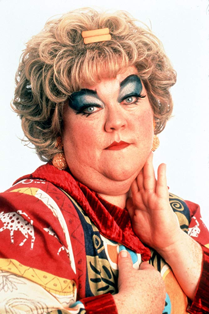 Mimi from the Drew Carey Show, a fat woman who is seen with a great deal of fatphobia and weight stigma. She's a fat woman wearing clown-like makeup and posing coyly.