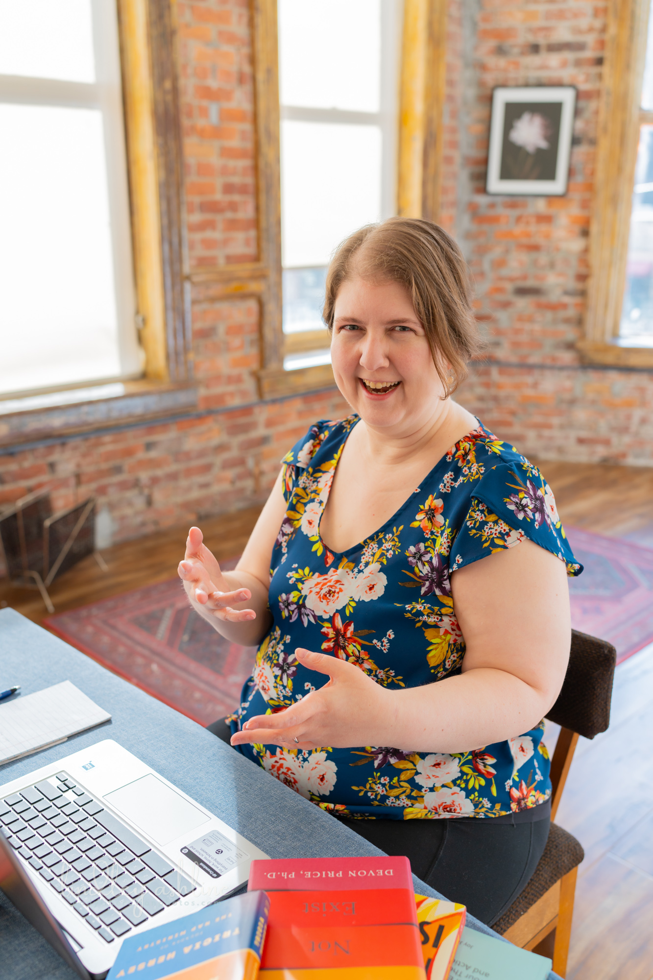 A plus-size white woman in a sleeveless top gestures during a telehealth therapy session in Washington state at a Pacific Northwest fat-positive business branding photo shoot.