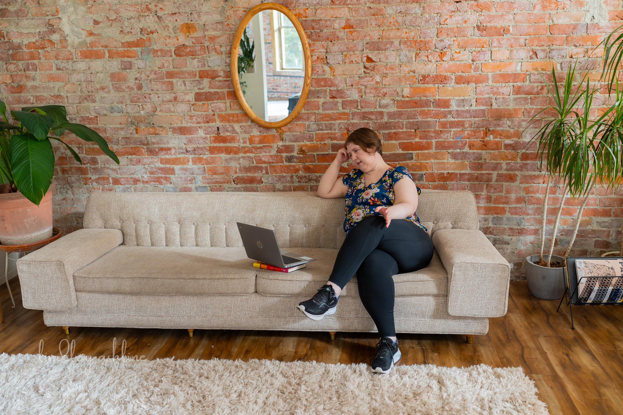 A plus-size white woman in a sleeveless top gestures during a telehealth therapy session in Washington state at a Pacific Northwest fat-positive business branding photo shoot.