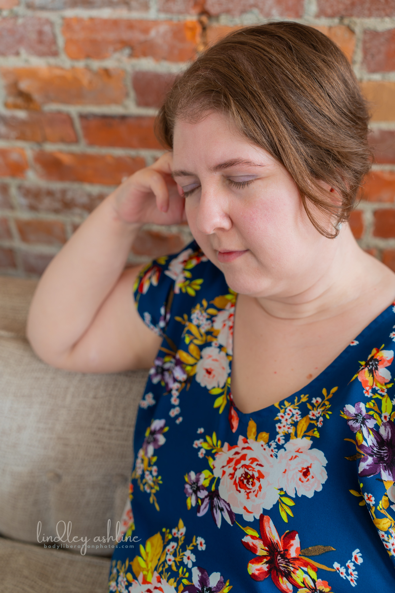 A plus-size white woman in a sleeveless top rests on a couch at a Seattle fat-positive business branding photo shoot.