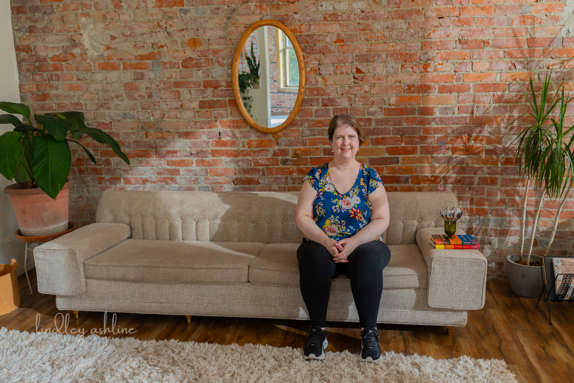 A plus-size white woman in a sleeveless top rests on a couch at a Seattle fat-positive business branding photo shoot.