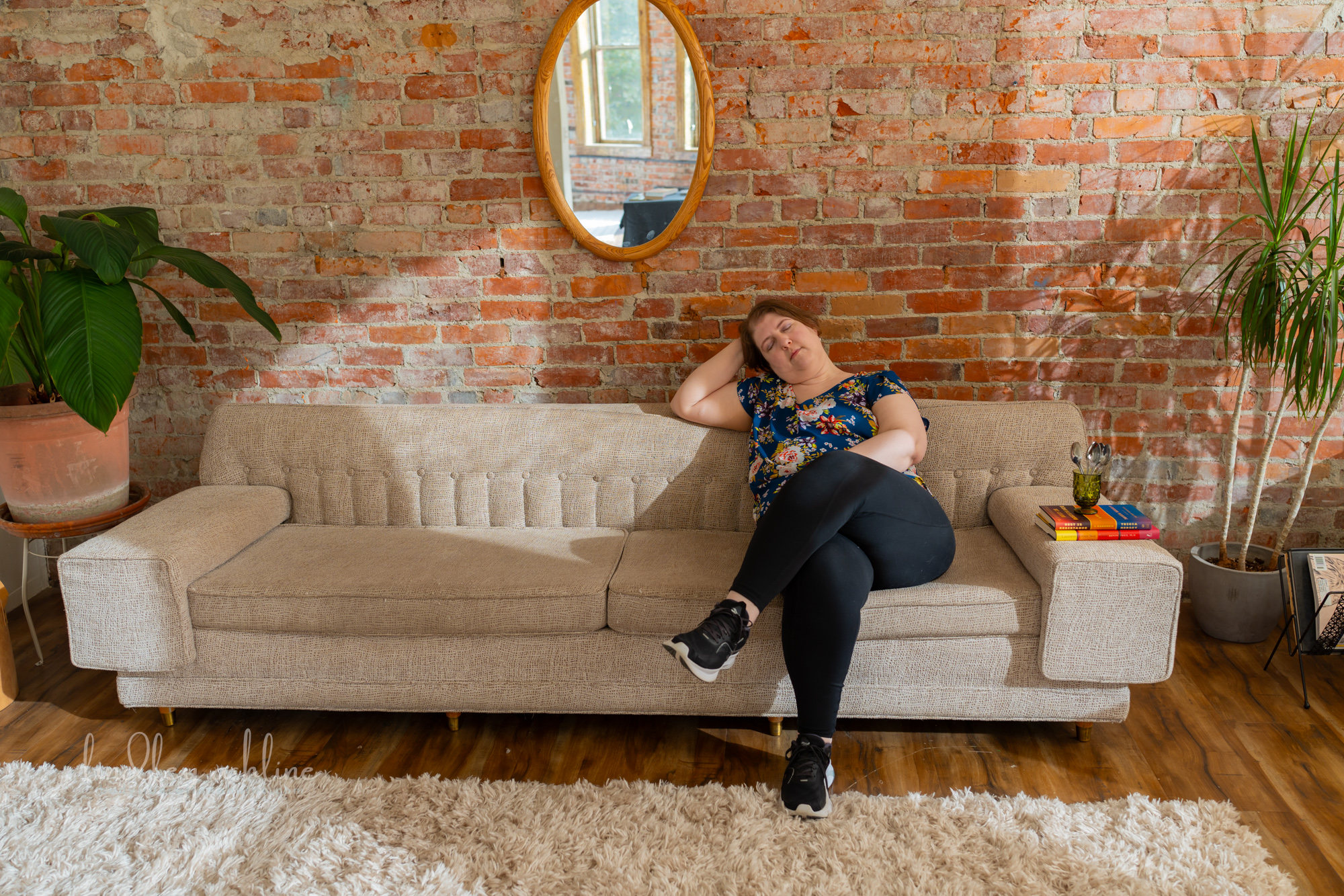 A plus-size white woman in a sleeveless top rests on a couch at a Seattle fat-positive business branding photo shoot.