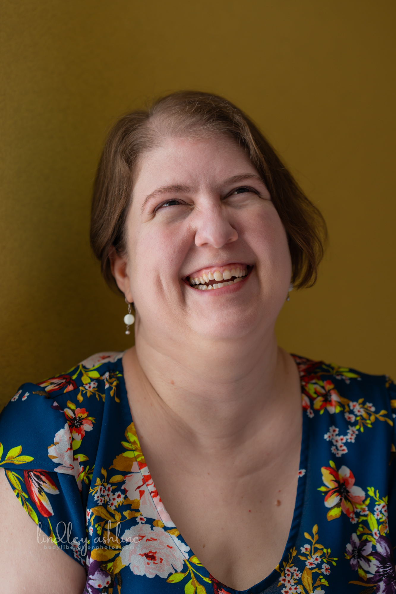 A plus-size white woman in a sleeveless top gestures during a telehealth therapy session in Washington state at a Pacific Northwest fat-positive business branding photo shoot.
