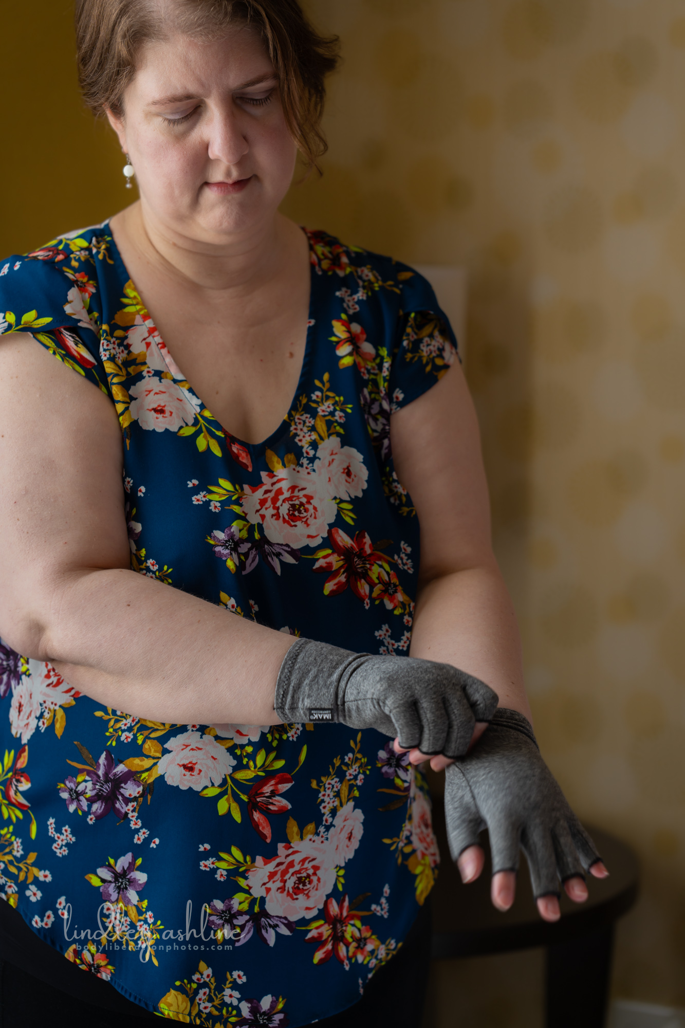A chronically ill plus-size white woman pulls on a compression glove at a Seattle body-positive business branding session.
